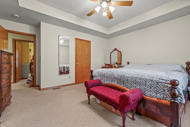 bedroom with ceiling fan, a raised ceiling, and light carpet