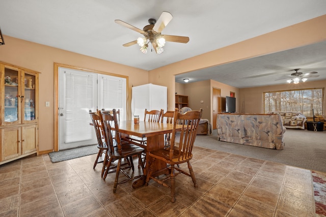 carpeted dining area with ceiling fan