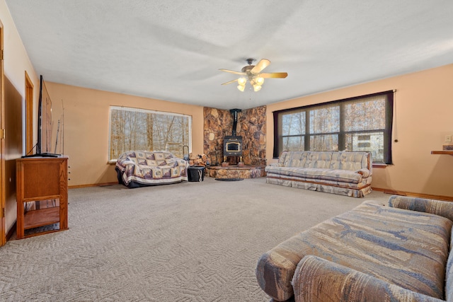 carpeted living room with a textured ceiling, a wood stove, and ceiling fan