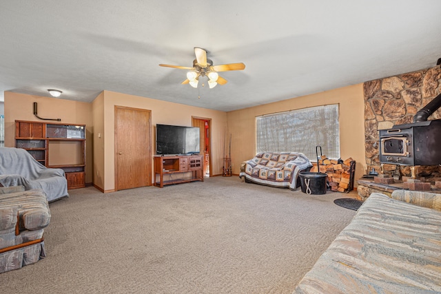 living room featuring carpet, a wood stove, and ceiling fan