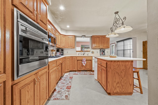 kitchen with a center island, sink, stainless steel appliances, decorative light fixtures, and a breakfast bar