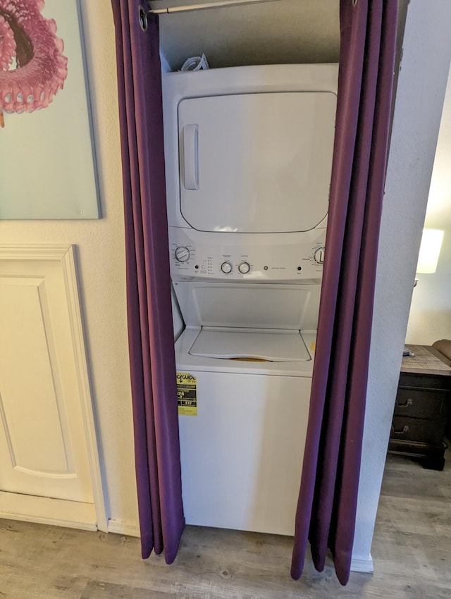 laundry room featuring light hardwood / wood-style floors and stacked washer / drying machine