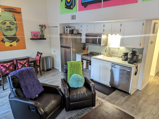 kitchen featuring white cabinets, appliances with stainless steel finishes, light hardwood / wood-style floors, and sink