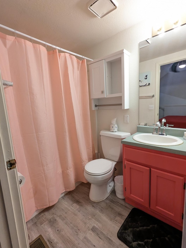 bathroom with vanity, a textured ceiling, hardwood / wood-style floors, toilet, and curtained shower