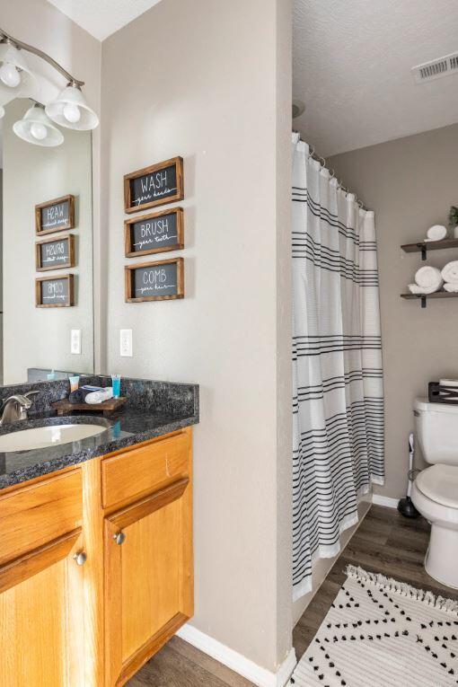 bathroom featuring walk in shower, toilet, vanity, and hardwood / wood-style flooring