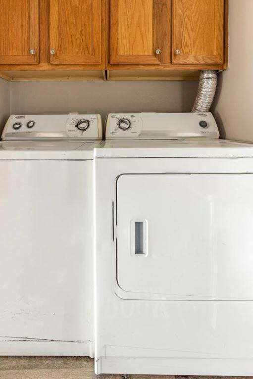 clothes washing area with cabinets and washer and clothes dryer