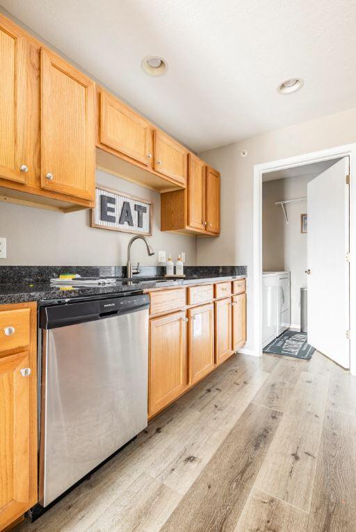 kitchen featuring sink, light wood-type flooring, stainless steel dishwasher, and washing machine and clothes dryer