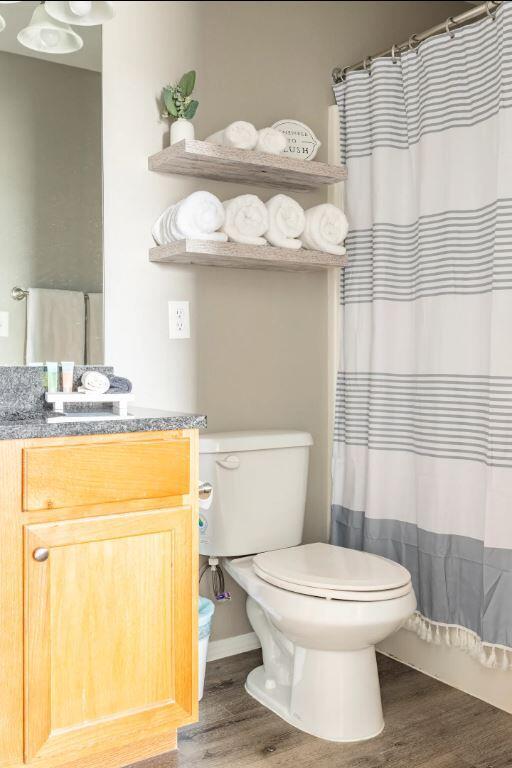 bathroom featuring vanity, hardwood / wood-style flooring, toilet, and walk in shower