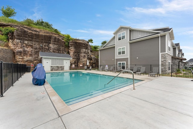 view of pool featuring a patio and a storage shed