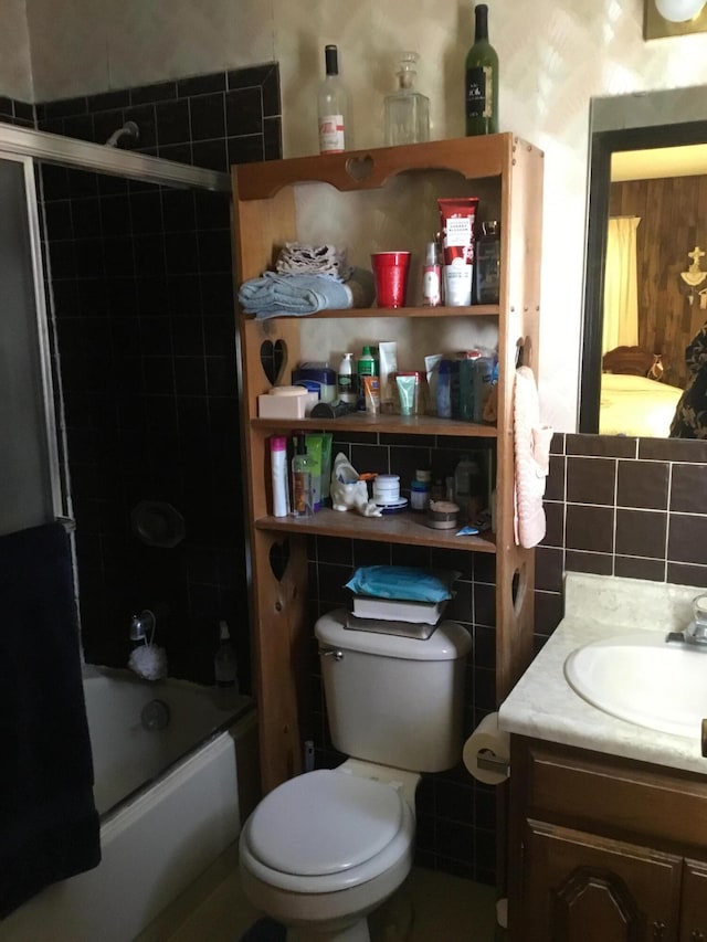 full bathroom featuring decorative backsplash, bath / shower combo with glass door, vanity, tile walls, and toilet