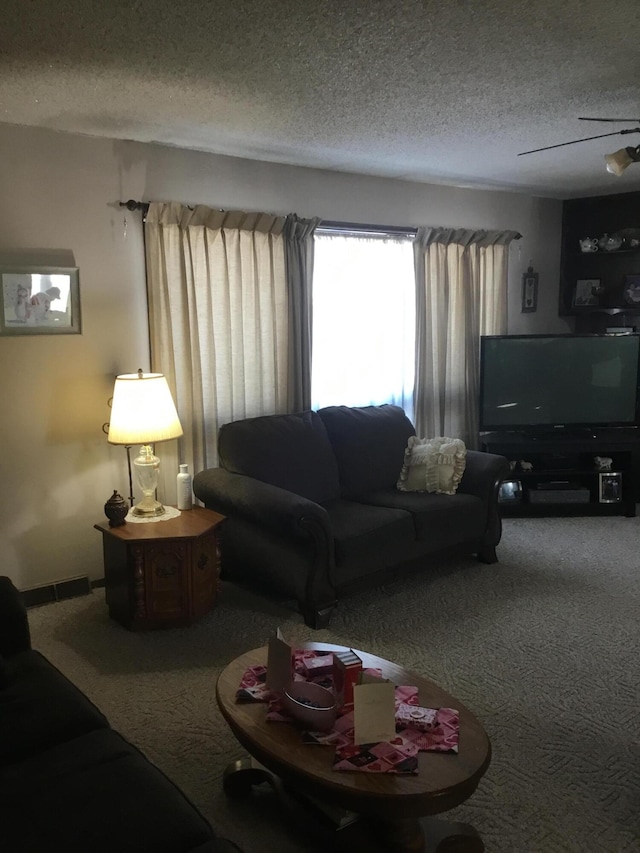 carpeted living room featuring a textured ceiling and ceiling fan