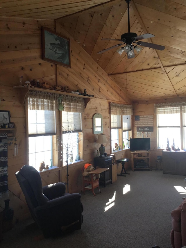 carpeted living area featuring vaulted ceiling, wooden walls, wooden ceiling, and ceiling fan