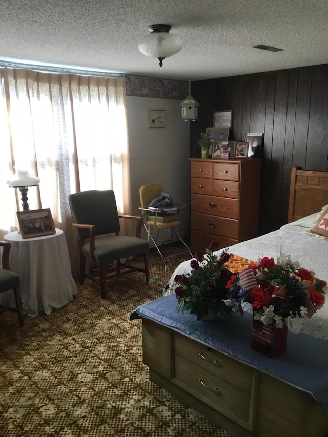 bedroom with wood walls, carpet, and a textured ceiling