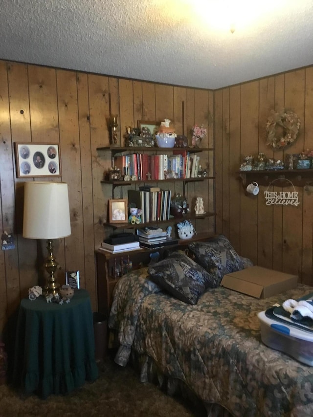 bedroom featuring a textured ceiling and wooden walls