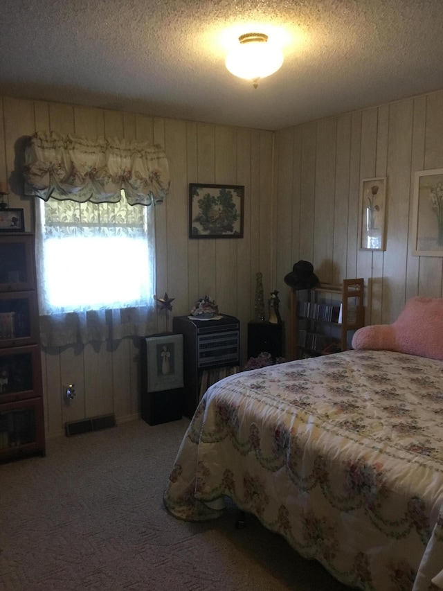 carpeted bedroom featuring wooden walls and a textured ceiling