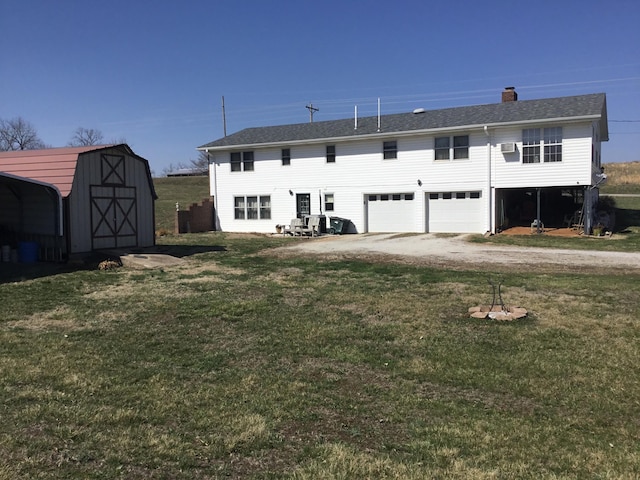 rear view of property with a lawn, a chimney, an outdoor structure, and driveway