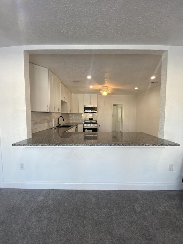 kitchen featuring white cabinetry, kitchen peninsula, and range