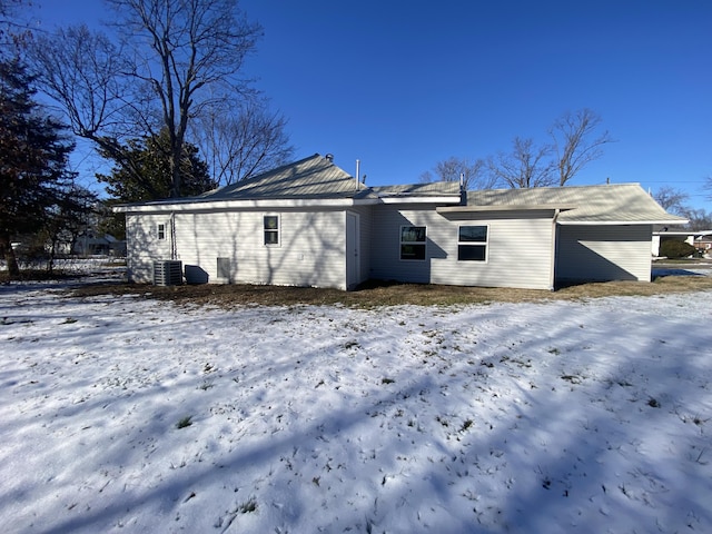 snow covered back of property featuring central AC