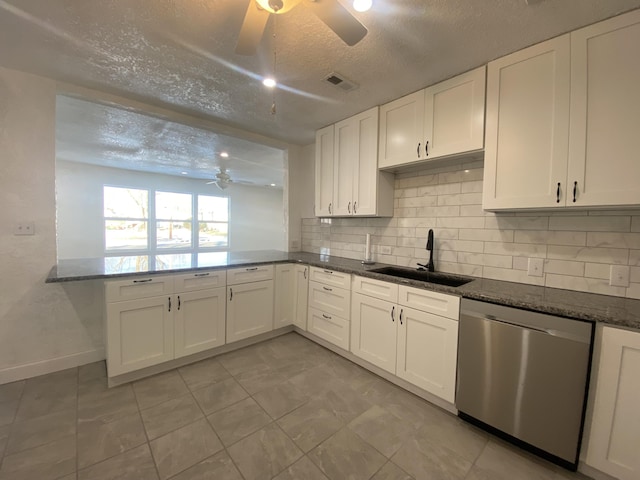 kitchen featuring dishwasher, sink, dark stone countertops, a textured ceiling, and white cabinetry