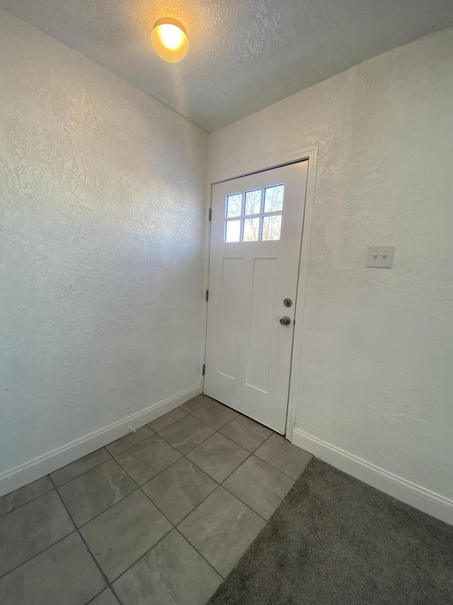 doorway to outside featuring tile patterned flooring and a textured ceiling