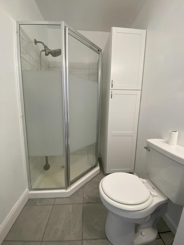 bathroom featuring tile patterned flooring, toilet, and a shower with shower door