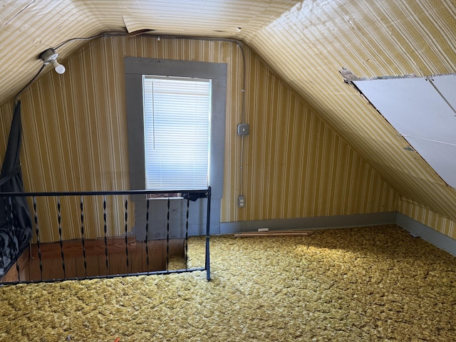 bonus room with carpet flooring, wooden walls, and vaulted ceiling