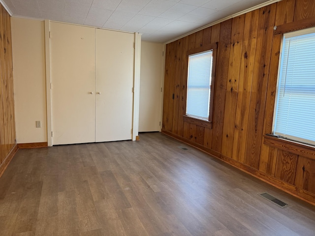 unfurnished bedroom featuring hardwood / wood-style flooring, crown molding, and wood walls