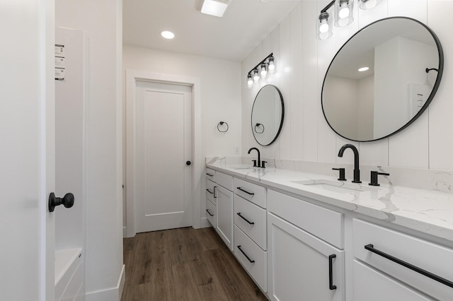 bathroom with double vanity, a sink, and wood finished floors