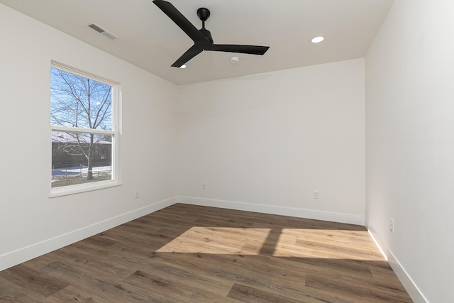 spare room featuring a ceiling fan, visible vents, baseboards, and wood finished floors