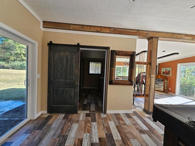 entrance foyer featuring dark hardwood / wood-style flooring, a wealth of natural light, vaulted ceiling, and a barn door