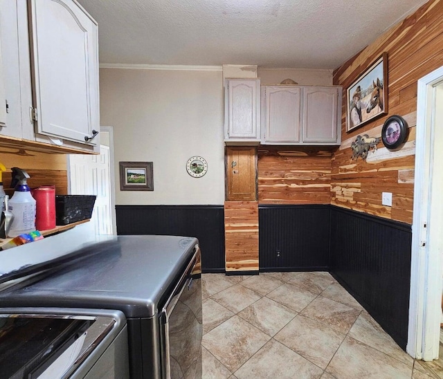 washroom featuring wood walls, washer and dryer, light tile patterned floors, ornamental molding, and a textured ceiling