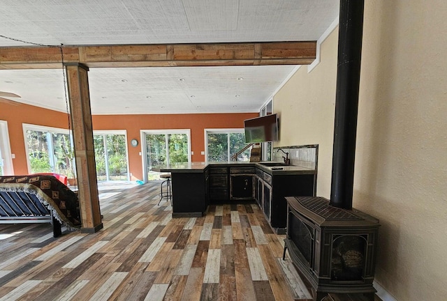 interior space featuring hardwood / wood-style floors, kitchen peninsula, a wood stove, and sink