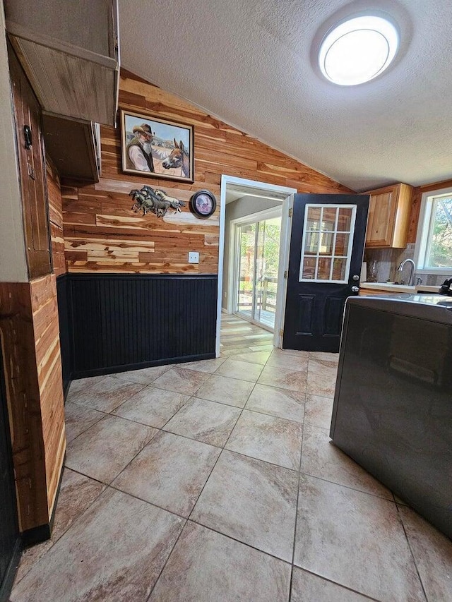 kitchen featuring vaulted ceiling and wood walls