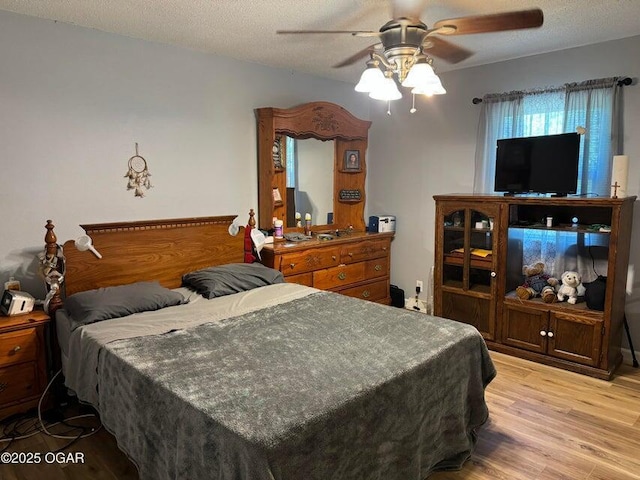 bedroom featuring ceiling fan, a textured ceiling, and light wood-type flooring