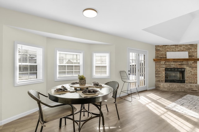 dining room featuring light wood-type flooring and a brick fireplace