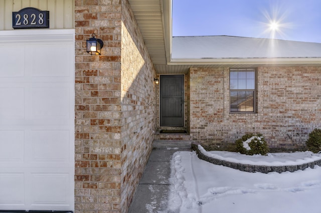 snow covered property entrance with a garage