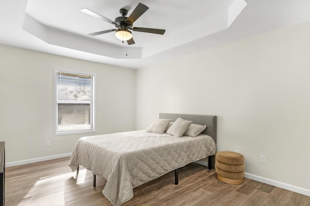 bedroom with a tray ceiling, light hardwood / wood-style flooring, and ceiling fan