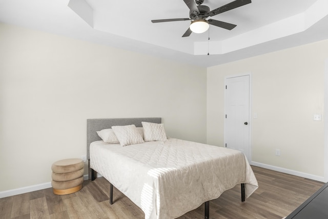 bedroom featuring wood-type flooring, a raised ceiling, and ceiling fan