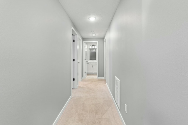 hallway with light colored carpet and a textured ceiling