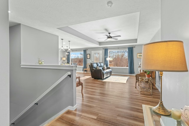 living room featuring a raised ceiling, hardwood / wood-style floors, and ceiling fan