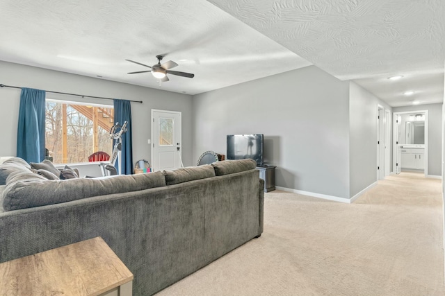 living room featuring ceiling fan, light colored carpet, and a textured ceiling