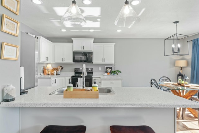 kitchen with hanging light fixtures, a breakfast bar, white cabinets, and black appliances