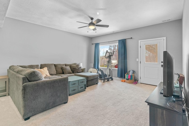 carpeted living room with a textured ceiling and ceiling fan