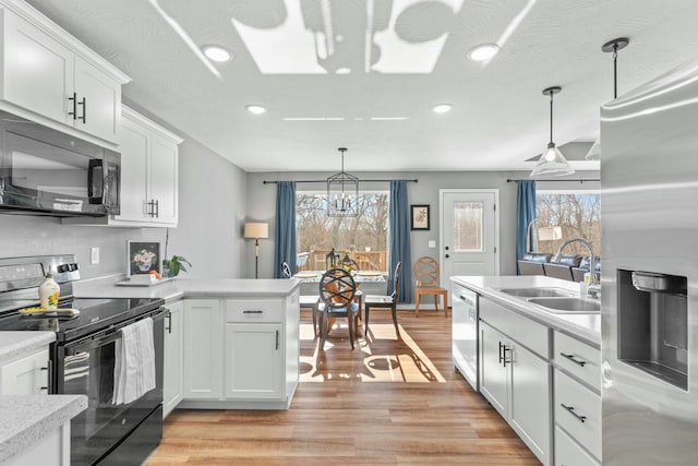 kitchen with sink, hanging light fixtures, stainless steel appliances, white cabinets, and a chandelier