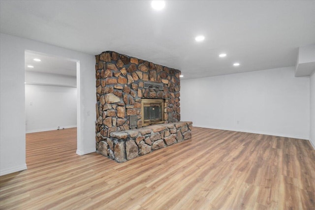 living room with a stone fireplace and light hardwood / wood-style flooring