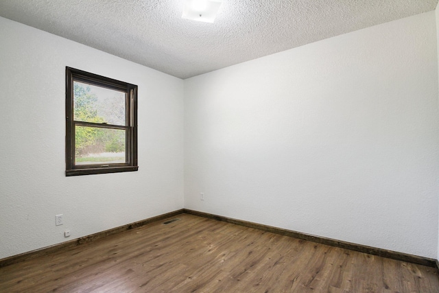 unfurnished room with dark hardwood / wood-style floors and a textured ceiling