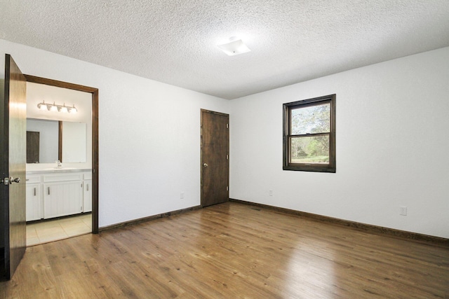 unfurnished room with a textured ceiling and light wood-type flooring