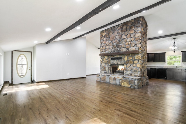 unfurnished living room featuring a stone fireplace, dark hardwood / wood-style flooring, lofted ceiling with beams, and sink