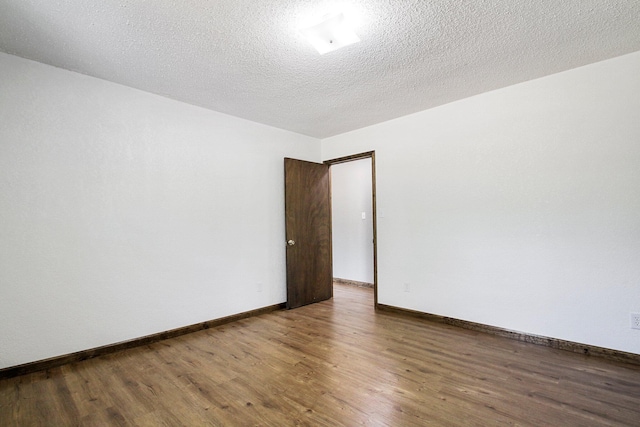 empty room with a textured ceiling and dark hardwood / wood-style flooring