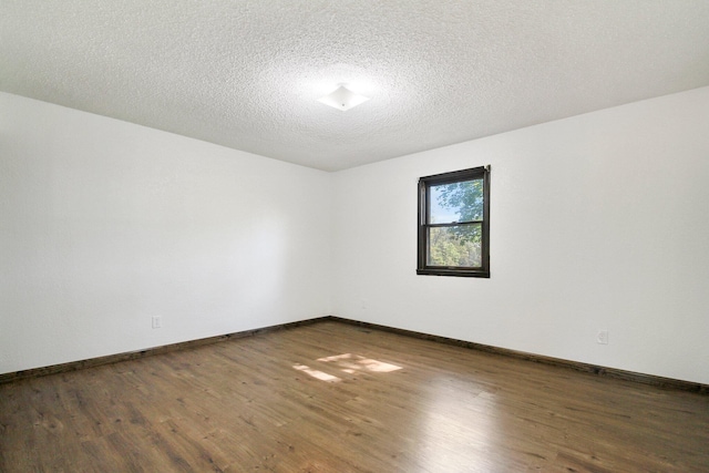 unfurnished room featuring a textured ceiling and dark hardwood / wood-style flooring